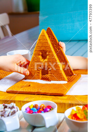 Familiy building a sweet ginger bread house Familiy building a sweet ginger bread house 47793399
