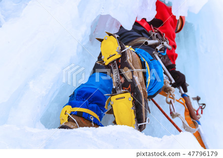 ice climber on a vertical wall of a frozen waterfall, bottom up 47796179