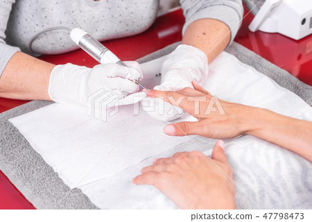 Professional manicure process, cleaning the nails with a manicure milling cutter, at beutician salon Professional manicure process, cleaning the nails with a manicure milling cutter, at beutician salon 47798473