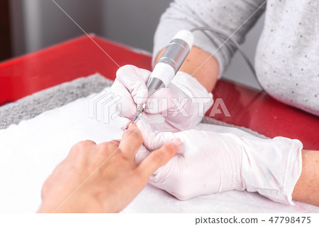 Professional manicure process, cleaning the nails with a manicure milling cutter, at beutician salon Professional manicure process, cleaning the nails with a manicure milling cutter, at beutician salon 47798475