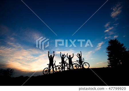 Silhouettes of cyclists standing on hill. Silhouettes of cyclists standing on hill. 47799920