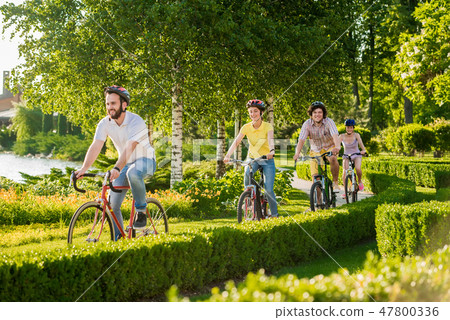 Four cheerful friends cycling outside. 47800336