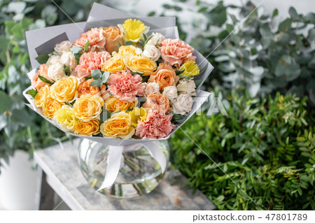beautiful fresh cut bouquet of mixed flowers in vase on wooden table. The work of the florist at a beautiful fresh cut bouquet of mixed flowers in vase on wooden table. The work of the florist at a 47801789