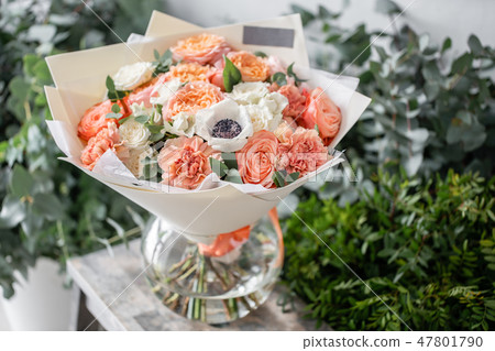 beautiful fresh cut bouquet of mixed flowers in vase on wooden table. The work of the florist at a beautiful fresh cut bouquet of mixed flowers in vase on wooden table. The work of the florist at a 47801790