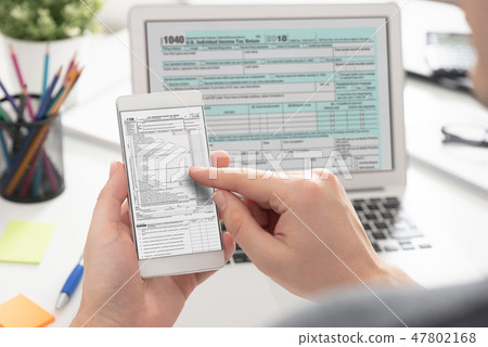 Man filling tax information using mobile devices Man filling tax information using mobile devices 47802168