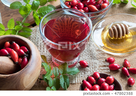 A cup of rose hip tea with fresh rose hips A cup of rose hip tea with fresh rose hips 47802388