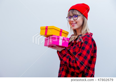 woman in red shirt and hat holding holiday gift boxes 47802679