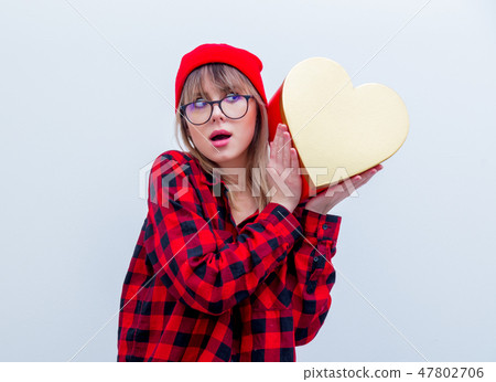 woman in red shirt and hat holding heart shape gift box 47802706
