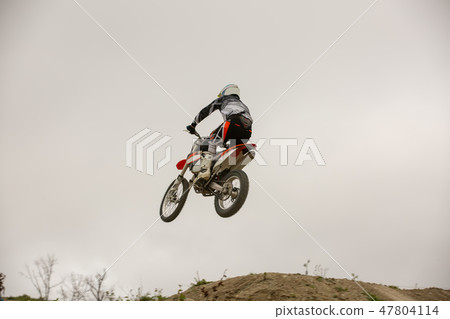 Racer on motorcycle participates in motocross cross-country in flight, jumps and takes off on Racer on motorcycle participates in motocross cross-country in flight, jumps and takes off on 47804114
