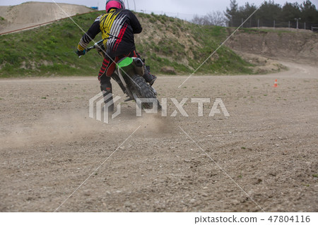 Professional Motocross Motorcycle Rider Drives Over the Road Track. Professional Motocross Motorcycle Rider Drives Over the Road Track. 47804116