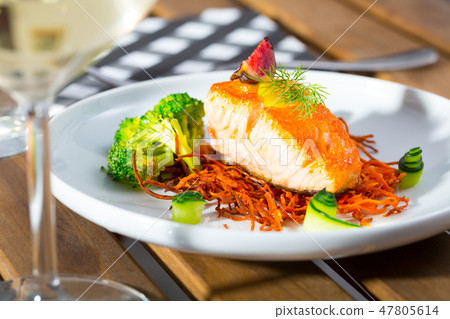 Tasty fried salmon on a pillow of smoked carrots, broccoli and fig on plate Tasty fried salmon on a pillow of smoked carrots, broccoli and fig on plate 47805614