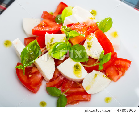 Plate of salad with cheese and tomatoes 47805909