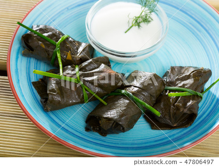 Grape rolls Sarni cooked in leaves and served with sour cream at plate 47806497