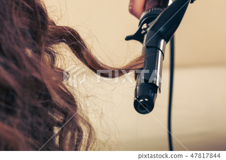 Stylist curling hair for young woman. Stylist curling hair for young woman. 47817844