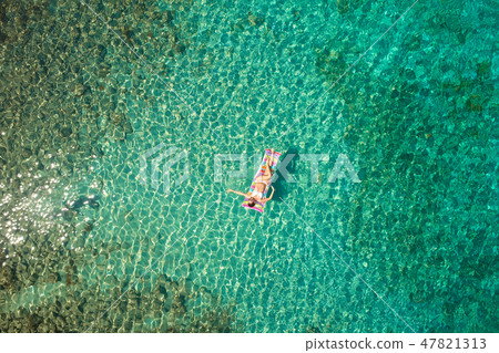 Top down view of a beautiful woman in a white bikini who is floa Top down view of a beautiful woman in a white bikini who is floa 47821313
