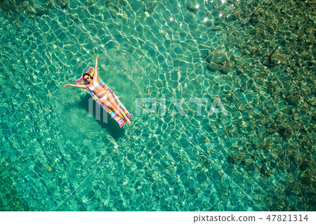 Top down view of a beautiful woman in a white bikini who is floa 47821314