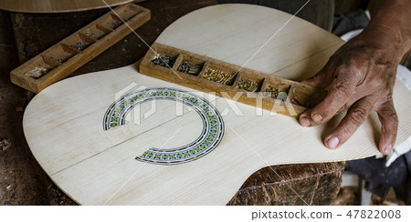 Man puts finishing touches on the inlay around a soundhole 47822008