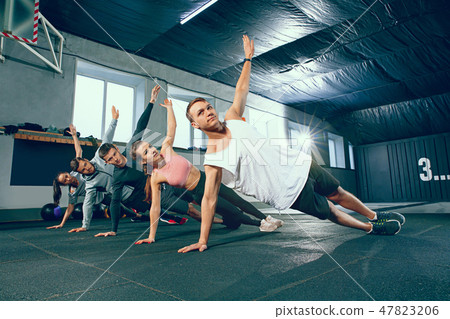 Shot of young men and a woman standing in plank position at the gym 47823206