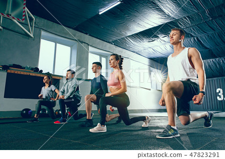 Shot of young men and a woman standing in plank position at the gym Shot of young men and a woman standing in plank position at the gym 47823291