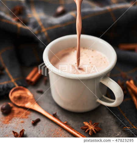 Pouring tasty hot cocoa drink into retro mug 47823295