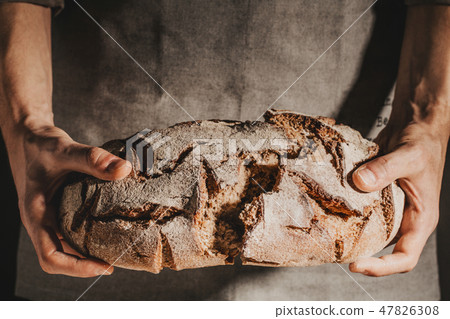 Baker or chef holding fresh made bread 47826308