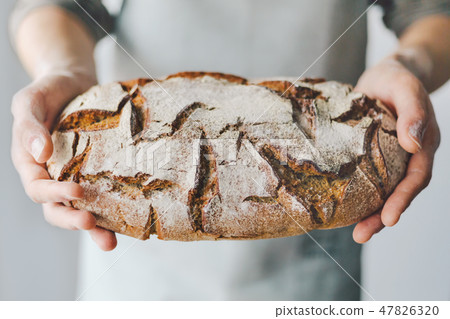 Baker or chef holding fresh made bread Baker or chef holding fresh made bread 47826320