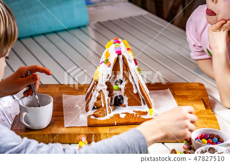Familiy building a sweet ginger bread house Familiy building a sweet ginger bread house 47827510