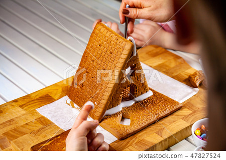Familiy building a sweet ginger bread house Familiy building a sweet ginger bread house 47827524