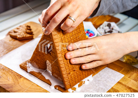 Familiy building a sweet ginger bread house Familiy building a sweet ginger bread house 47827525