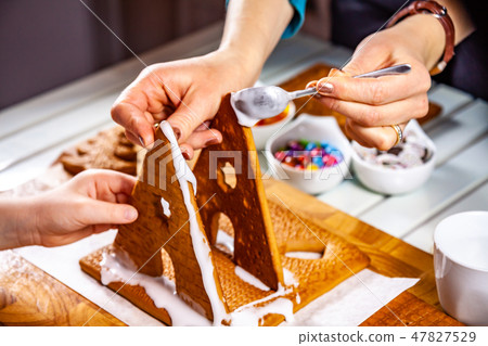 Familiy building a sweet ginger bread house 47827529