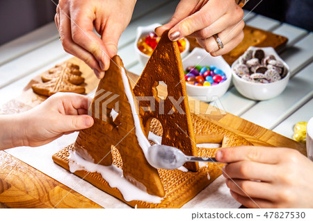 Familiy building a sweet ginger bread house Familiy building a sweet ginger bread house 47827530