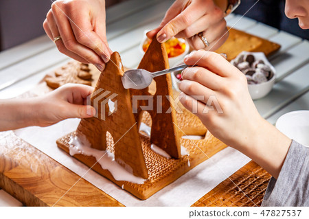 Familiy building a sweet ginger bread house Familiy building a sweet ginger bread house 47827537