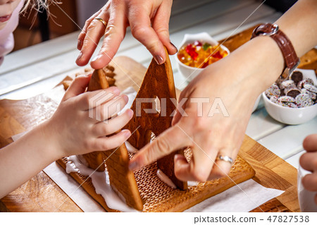 Familiy building a sweet ginger bread house Familiy building a sweet ginger bread house 47827538