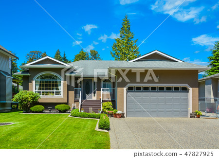 Suburban family house with nice lawn, wide garage door, and concrete driveway 47827925