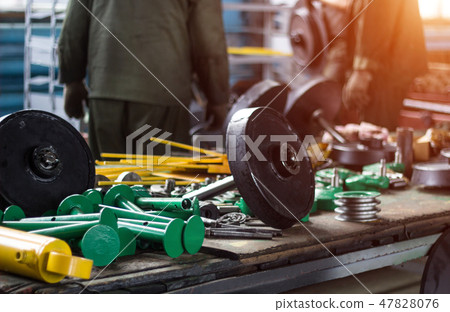 Workers at the plant collect assemblies and units for tractors in the shop, sunset, assembly of Workers at the plant collect assemblies and units for tractors in the shop, sunset, assembly of 47828076