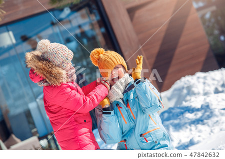 Winter vacation. Family time together outdoors daughter playing with mother taking off her hat 47842632