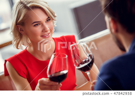 Young couple on date in restaurant sitting drinking wine cheers close-up woman looking at man Young couple on date in restaurant sitting drinking wine cheers close-up woman looking at man 47842938