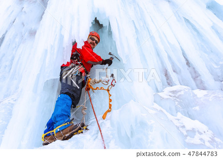 ice climber on a vertical wall of frozen waterfall 47844783