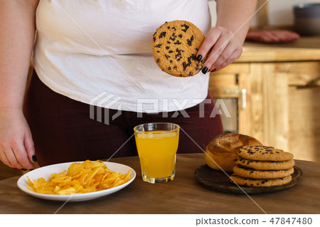 overweight woman eating sugary foods drinking soda overweight woman eating sugary foods drinking soda 47847480