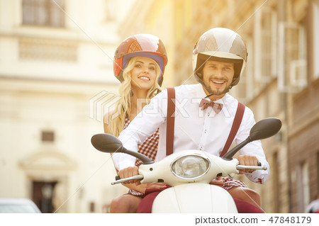 Hipster couple riding a scooter on a sunny day Hipster couple riding a scooter on a sunny day 47848179