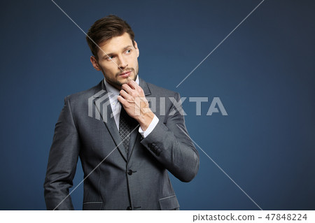 Handsome young business man standing on blue background Handsome young business man standing on blue background 47848224