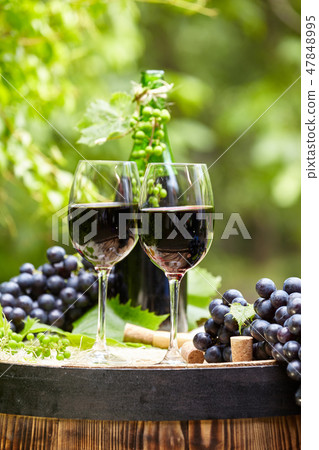 Red wine bottle and wine glass on wodden barrel. 47848995