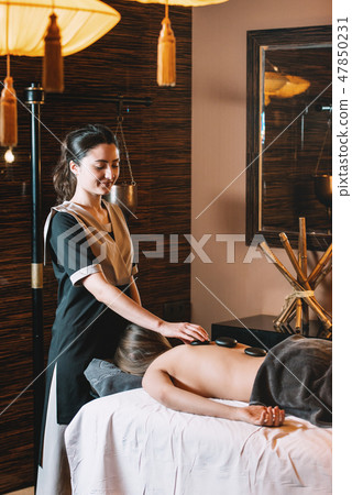 Specialist making hot stone massage to a client. 47850231