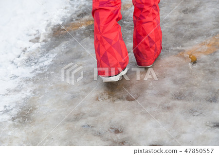 The feet of a woman walking on the frozen parking lot of the slopes 47850557