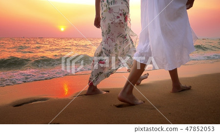 close up . bare feet on the beach. two young women in white dress walking on the beach at sunset close up . bare feet on the beach. two young women in white dress walking on the beach at sunset 47852053