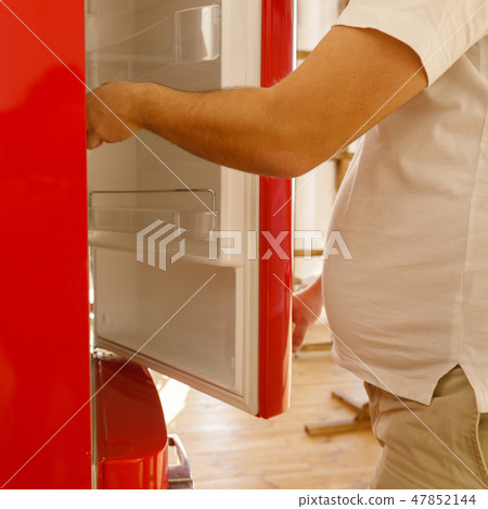 obese man plunging into fridge looking for snack 47852144
