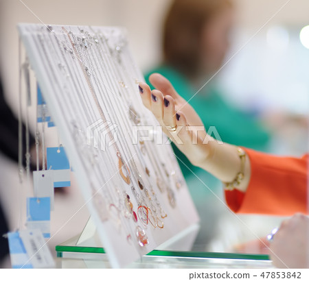 Woman choosing pendant in shop or markets. 47853842