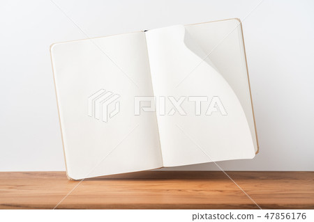 Perspective view of kraft notebook on wood floor 47856176