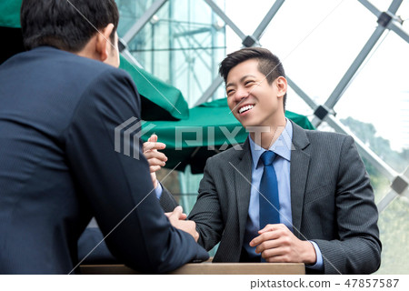 Young Asian business partners talking at cafe Young Asian business partners talking at cafe 47857587