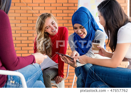 Diverse women looking at tablet computer together 47857762